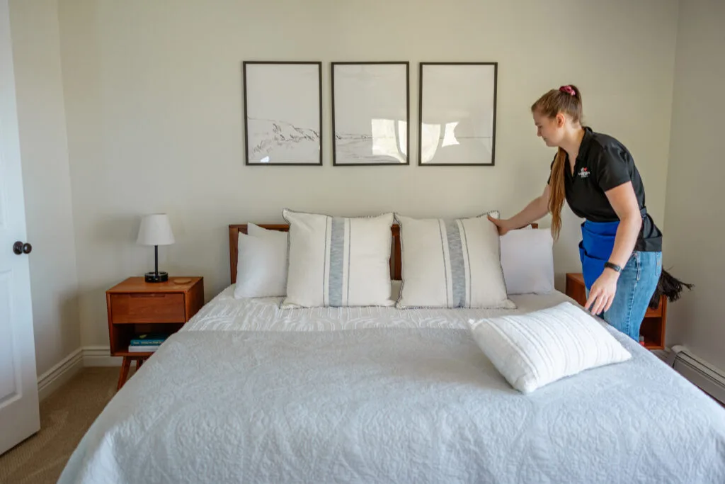 Technician making the bed during a rental make-ready clean in northern Michigan