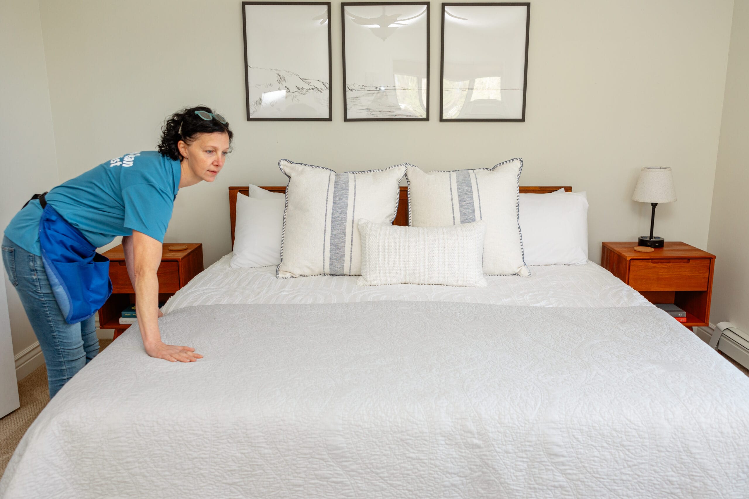 Cleaning technician smoothing a freshly made bed